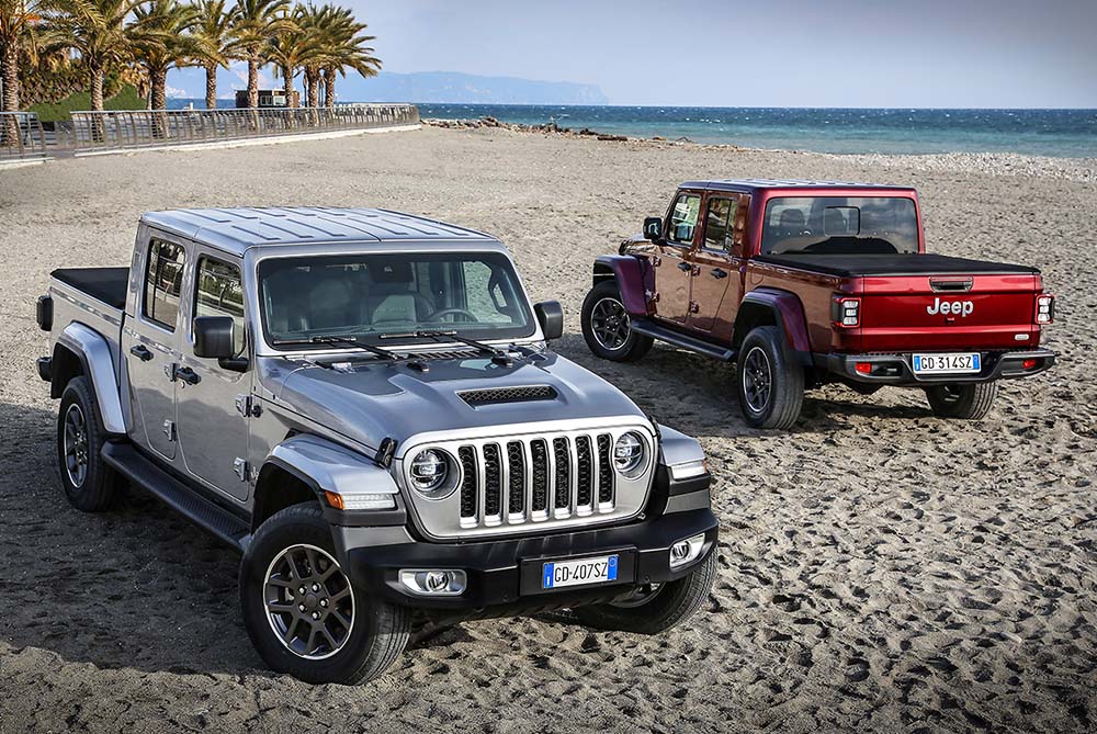 A silver and red Jeep Gladiator parked on a beach