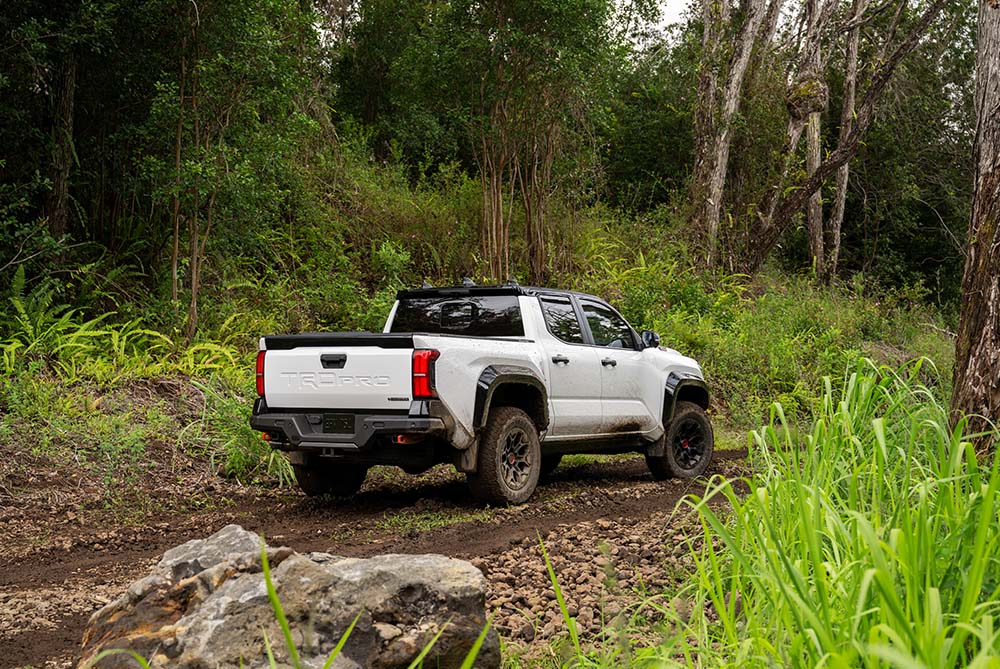 Toyota Tacoma driving through a muddy trail in the forest