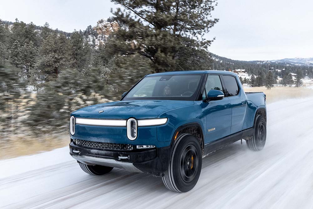 A Rivian R1T driving over an icy road