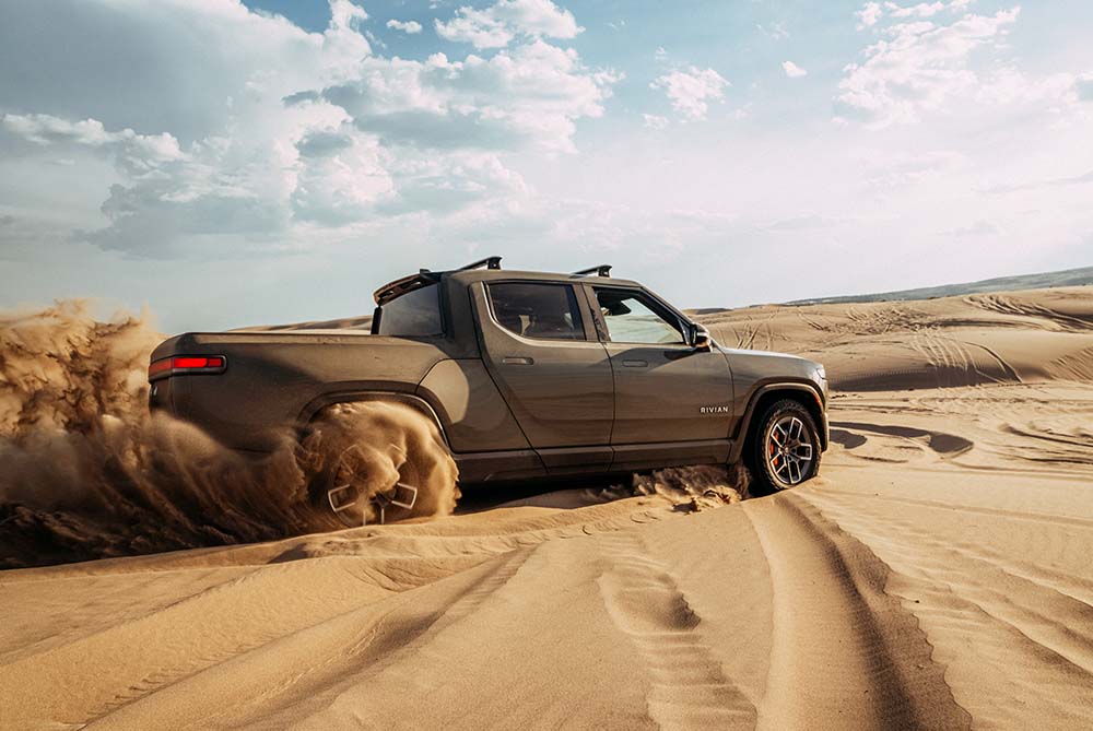 A green pickup drifting on a sandy desert