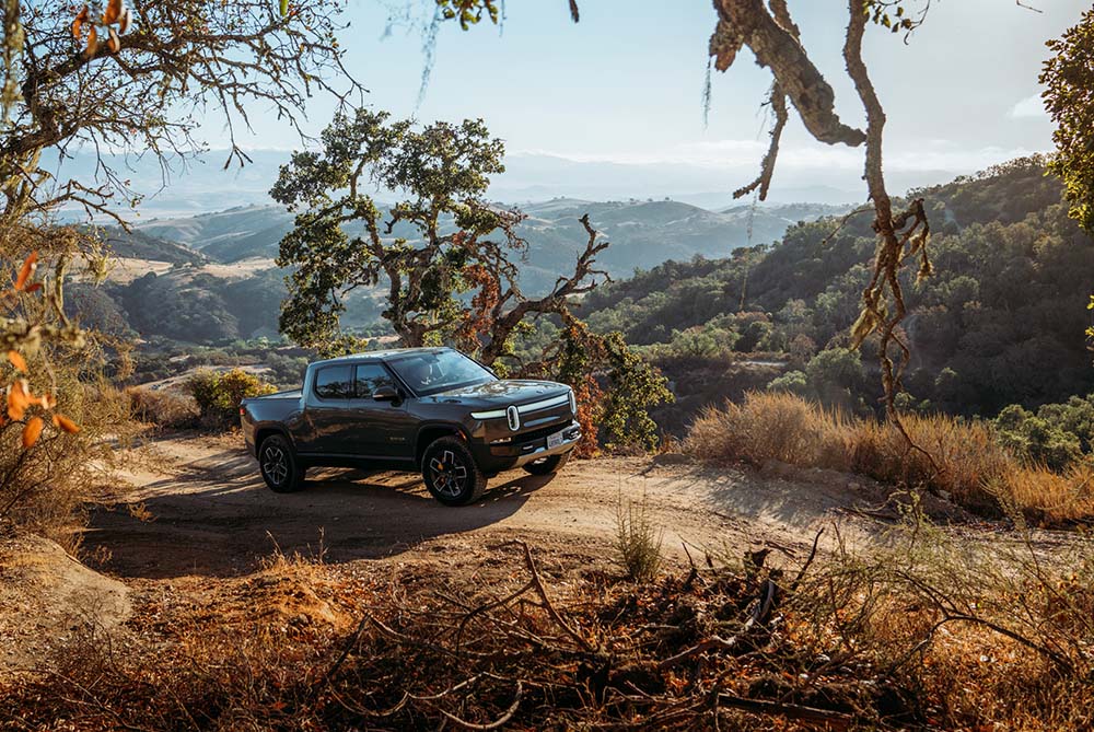 A Rivian R1T on a dusty trail in the countryside