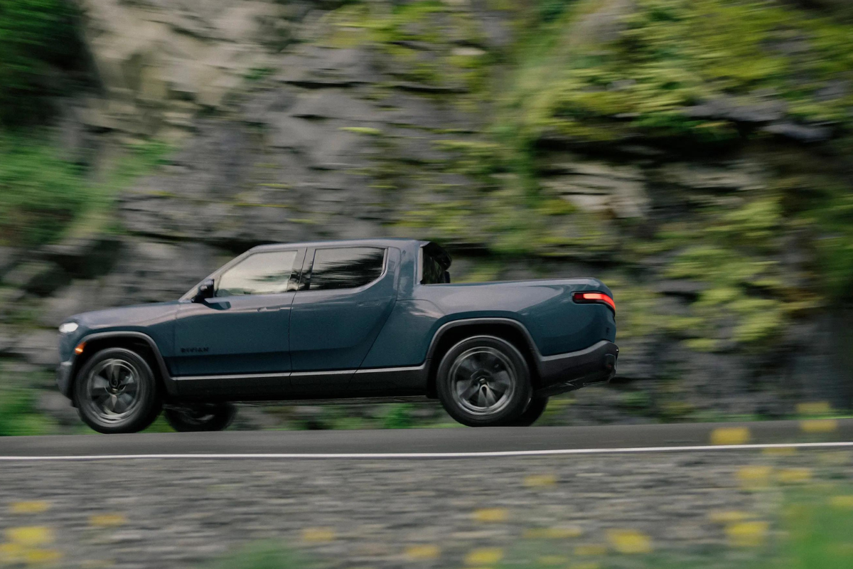 The futuristic Rivian R1T electric truck cruises down a scenic highway