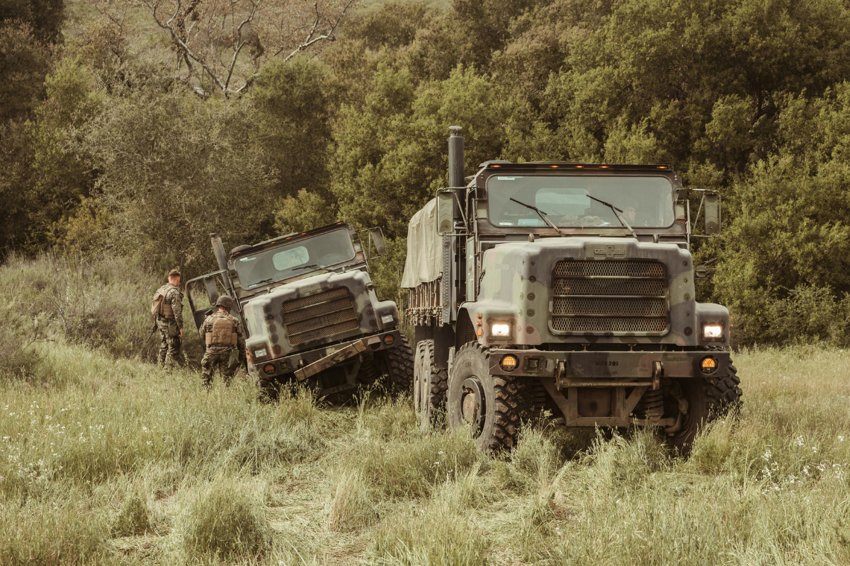 Military trucks driving through a forest