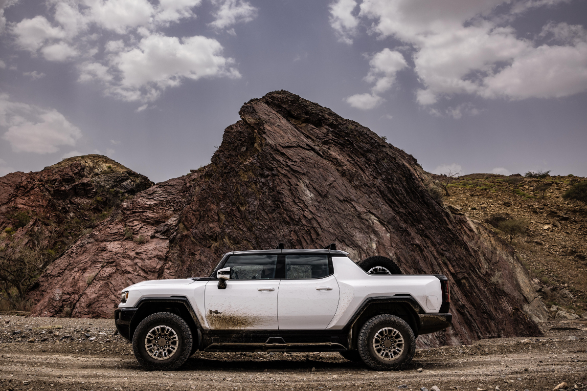 A white GMC Hummer cruising through a mountain range