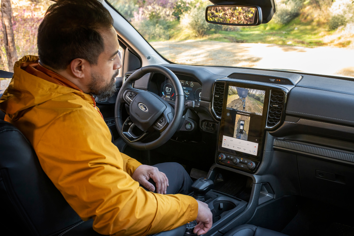 A man in a yellow coat looking at the infotainment system in his Ford Ranger