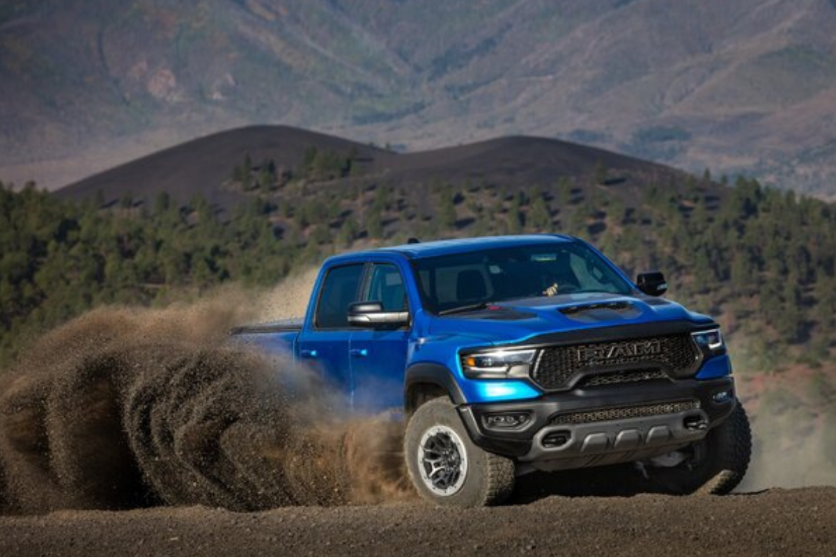 A blue RAM pickup truck kicking up dust